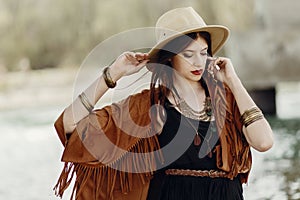 Stylish hipster woman posing in hat with windy hair, in fringe p