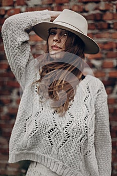 Stylish hipster woman posing in knitted sweater on background o