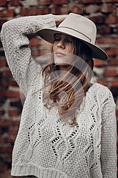 Stylish hipster woman posing in knitted sweater on background o