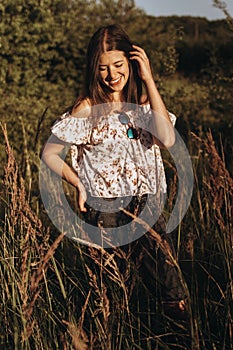 Stylish hipster woman smiling in wildflowers and enjoying moment