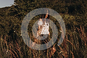 Stylish hipster woman walking in wildflowers and enjoying moment