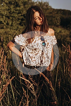 Stylish hipster woman walking in wildflowers and enjoying moment