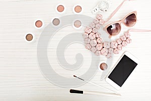 Stylish image of woman s accessories isolated above on light wood background. Pink ornamentation, necklace, phone