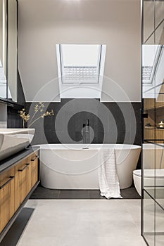 Stylish interior of bathroom with bathtub, shower, towels and other personal bathroom accessories. Modern and design interior.