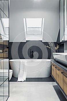 Stylish interior of bathroom with bathtub, shower, towels and other personal bathroom accessories. Modern and design interior