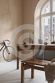 Stylish interior design of dining room with wooden dining table, bench and beautiful personal accessories. Modern home decor.