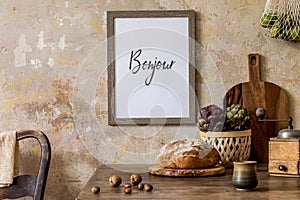 Stylish interior of kitchen space with wooden table, brown mock up photo frame, herbs, vegetables, tea pot, cups .