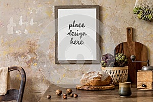 Stylish interior of kitchen space with wooden table, brown mock up photo frame, herbs, vegetables, tea pot, cups and kitchen.