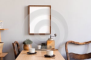 Stylish interior of kitchen space with wooden table with mock up photo frame, design chairs, decoration and furniture.