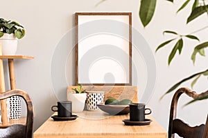 Stylish interior of kitchen space with wooden table with mock up photo frame, design chairs, decoration and furniture.