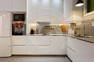 Stylish interior of modern kitchen with marble table top and household appliances.