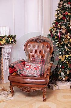 Stylish interior of room with Christmas fir tree and brown armchair. Beautiful cozy decorated living room for Christmas with firep