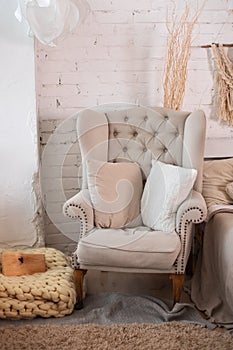 The stylish interior of the room with comfortable grey armchair and pillows. Cozy decorated living room for Christmas. Rustic home