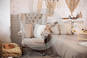 The stylish interior of the room with comfortable grey armchair and pillows. Cozy decorated living room for Christmas. Rustic home