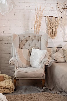 The stylish interior of the room with comfortable grey armchair and pillows. Cozy decorated living room for Christmas. Rustic home