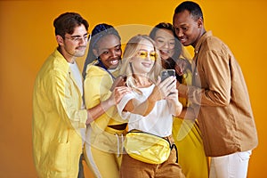 Stylish international group of young people take selfie isolated on yellow background