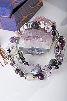 Stylish jewelry bracelet with semiprecious and amethyst  crystal around  white background. hobby and fashion concept. close up photo