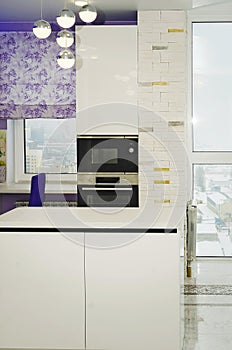 Stylish kitchen interior with white fronts and built-in oven and microwave. Vertical photography