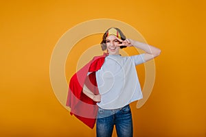 Stylish lady in funny paper crown posing with peace sign. Indoor photo of good-looking curly girl in princess costume..