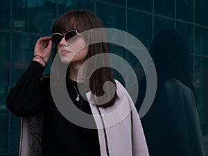 Stylish lady in sunglasses and light-coloured coat medium shot