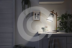 Stylish lamp and decor on white cabinet in room, space for text. Interior element