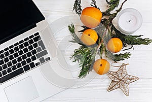 Stylish laptop and christmas oranges and golden star and candle