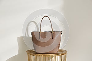 Stylish leather woman`s bag on table near  wall