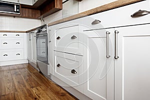 Stylish light gray handles on cabinets close-up, kitchen interior with modern furniture and stainless steel appliances. kitchen d photo