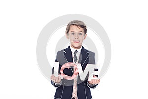 stylish little boy holding word love and smiling at camera