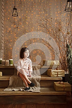 Stylish little girl in light pink dress sits in the christmas de