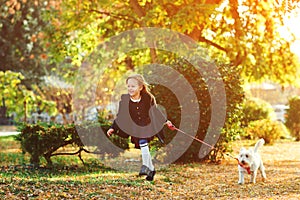 Stylish little girl running with her dog at nature. Child girl having fun with white terrier outdoors. Lifestyle portrait