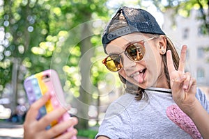 Stylish little girl in sunglasses taking a selfie outdoors