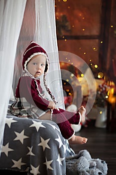 Stylish little toddler boy, playing around christmas decoration