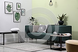 Stylish living room interior with comfortable green sofa and floral pictures