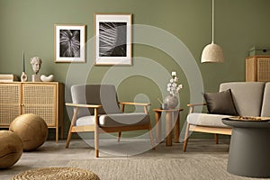 Stylish living room interior design with scandi armchair, elegant commodes, mocj up poster frames and accessories. Green wall.