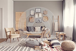 Stylish living room interior design with scandinavian settee, grey wall and natural accents