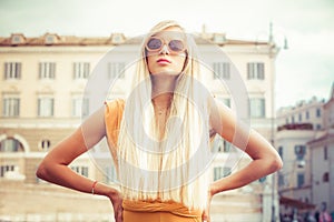 Stylish long blond hair young woman with sunglasses in the city