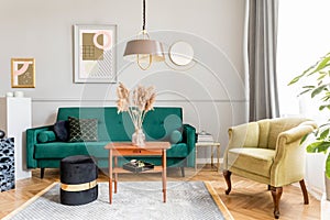 Stylish and luxury living room interior with elegant green velvet armchair, furniture, mock up posters, decoration.