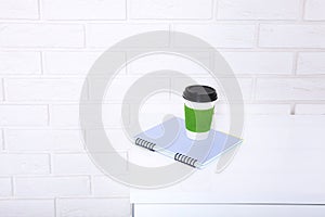 Stylish macro cup of coffee and notebook in office. Selective focus and copy space. Brick wall and workplace business concept.