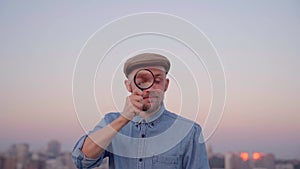 Stylish male looking using magnifying glass outdoor