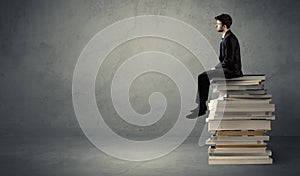 Stylish male seated on books