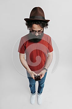 Stylish man with beard using smartphone in studio