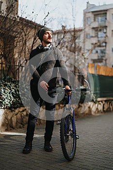 Stylish man with a bicycle looking away on a sunny day in the city