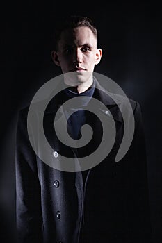 Stylish man in black coat in dark studio