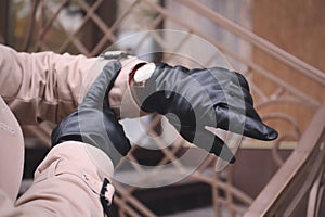 Stylish man in black leather gloves looking at his watch outdoors, closeup