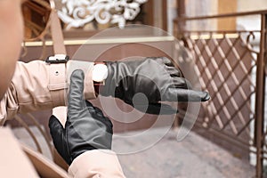 Stylish man in black leather gloves looking at his watch outdoors, closeup