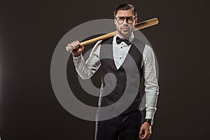 stylish man in bow tie and eyeglasses holding baseball bat and looking at camera