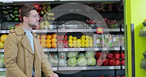Stylish man chooses apples in the supermarket. Healthy food, citrus fruits. Man selecting fresh apples in grocery store