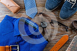Stylish man clothing and accessories flat lay in blue and brown colors on a wooden background