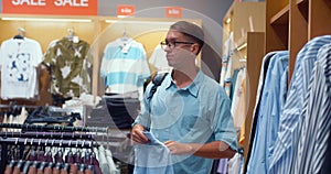 Stylish man comes shopping and chooses clothes in store. Shopper is dissatisfied with price-quality of selected shirt